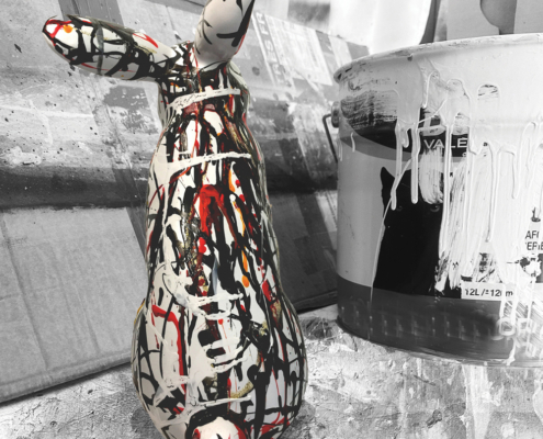 Sculpture de lapin Jean de Daphné Dejay dans l'atelier devant un pot de peinture qui coule